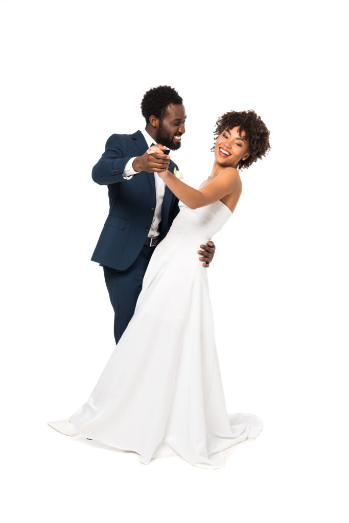 Bride and groom smiling while dancing together in a ballroom studio