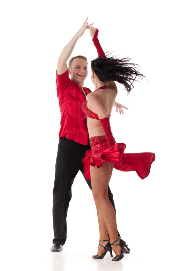 Smiling salsa dancers practicing partner moves in a bright dance studio